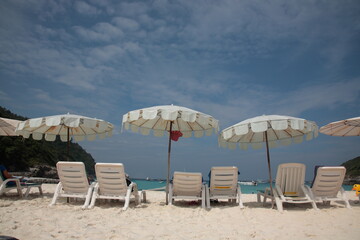 Tourists swimming and Snorkeling at beach with resort outdoor sunshade and chairs on the tropical island in Phuket, Thailand. 