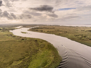 River Corrib, county Galway, one small motor boat moving toward the lake, Aerial drone shot, High angle