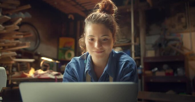 Close Up Portrait Of Pleasant Ginger Female Creative Fashion Designer Working With Laptop, Happy Pensive Artisan Using Computer Staying Online And Up To Date Connected Fast Internet In Workshop