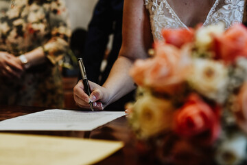close up of a person writing a letter. Detail of the hand of a bride sitting at the court table signing the wedding papers. bride signing