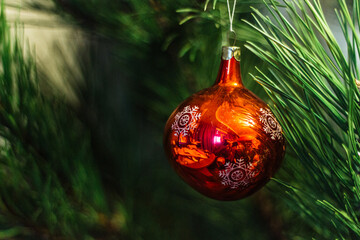 Christmas green background with red round toy on a branch of a christmas tree - 383808757