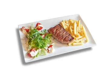 White plate with Beef steack, french fries and tomato on salad.