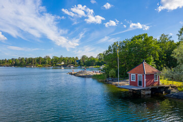 Fototapeta na wymiar Small red cottage by water in Stockholm archipelago in Sweden