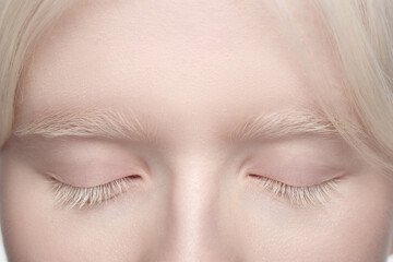 Eyes closed. Close up portrait of beautiful albino woman isolated on white studio background....
