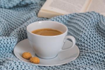 Cup of coffee on a light blue knitted wool blanket. Cozy atmosphere. Coffee break, stay at home concept.