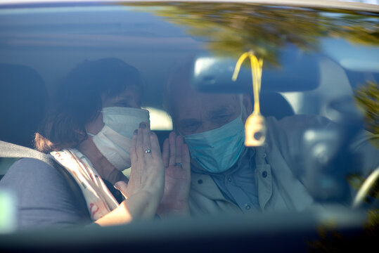 Happy Senior Couple Wearing Anti Virus Masks Are Driving In A Car During The COVID-19 Pandemic