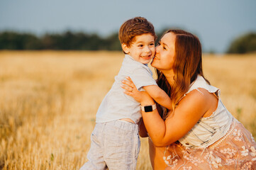 Cute cheerful child son with mother in field