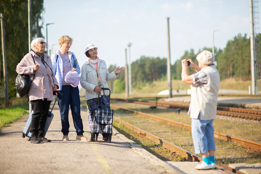Smiling senior women take a photo on a platform waiting for a train to travel during a COVID-19 pandemic