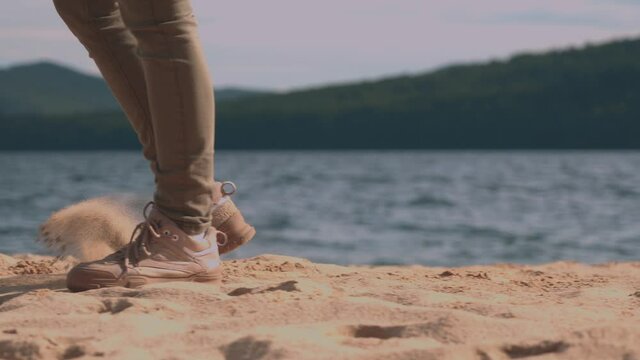 the girl walks along the beach on the shore, indifferently kicks the sand with her feet