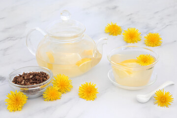 Immune boosting dandelion flower & lemon tea in a glass tea pot & cup with dried dandelion root. Lowers cholesterol, blood pressure and regulates blood sugar. High in antioxidants and vitamin c.  