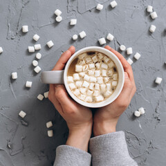 Woman holding cup of hot coffee on gray cemented back ground. Top view.