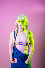 Hippy caucasian woman blowing bubble gum - Playful diverse young girl chewing gum isolated on pink background