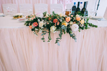 Wedding table decorated with bouquet with roses, eustoma and eucalyptus leaves.