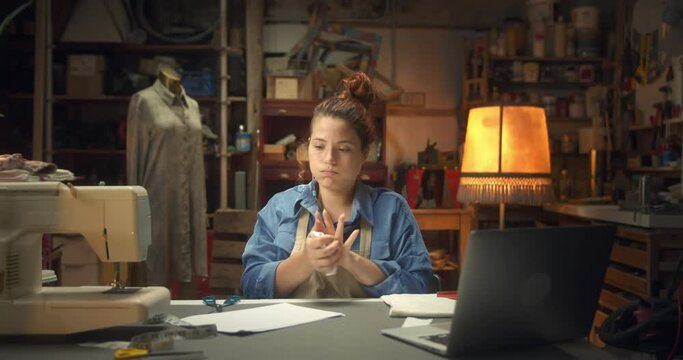 Beautiful female sadly throwing away paper unsuccessful project stressful moment indoors, depressive sad young woman artisan fashion designer in apron working sitting next to work-desk in workshop