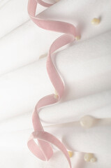 Pink curly ribbon and decorative beads on the white surface