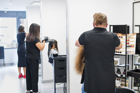 Hairdressers working standing up, with black clothes and black background