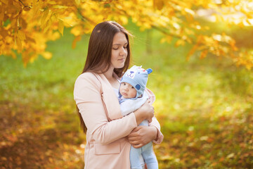 portraits of mom and baby in autumn park, mom hugs baby