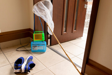玄関に置かれた虫取りの道具と子供の靴