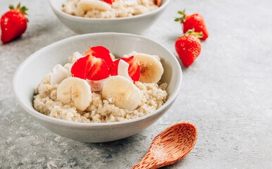 Quinoa porridge with coconut milk and fresh strawberries on light gray background. Healthy Lactose and Gluten Free Breakfast.