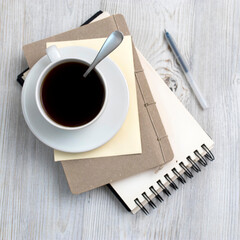 desk office with blank notepad, coffee cup and pen on wood table. Flat lay top view copy space.