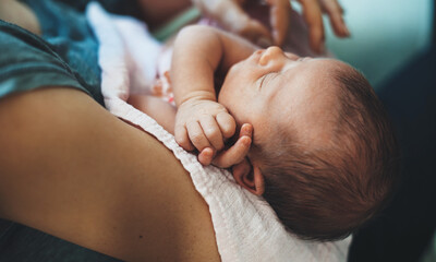 Small caucasian baby sleeping while his mother is holding him in arms