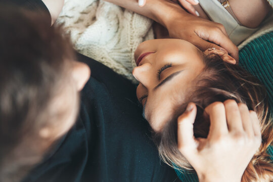Upper view photo of a caucasian lady lying on her boyfriend knees while he is playing with her hair