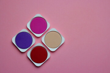 Palette of pink, lilac and red shades of watercolor paints on a pink background