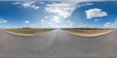 Full spherical seamless panorama 360 degrees angle view on no traffic old asphalt road among fields with clear sky and white clouds in equirectangular projection, VR AR content