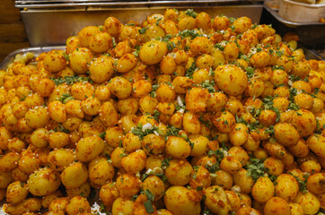 A lot of ried potato spheres with chilli and chopped green onion. Chinese street food.