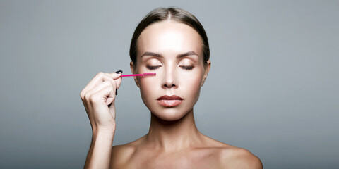beautiful young woman doing make-up,applies mascara