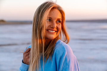 Young caucasian happy blonde woman smiling and looking aside outdoors