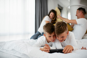 Obraz premium Two little brothers are playing games on the phone. Beautiful boys enjoying at home.