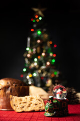 Christmas table. Details of a beautiful Christmas table with red tablecloth and a Christmas tree in the background. Low key image. Small depth of field, selective focus.