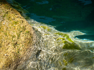 relaxing water stream with a green color, there is musk on the rocks and the water is a light turquoise color