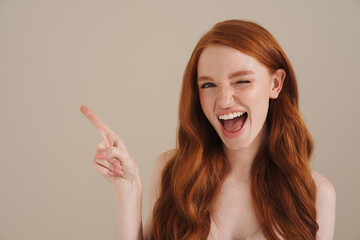 Ginger half-naked happy girl winking and pointing finger aside