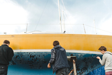 Men sticking masking tape on boat