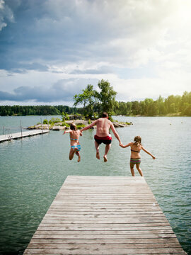 Father with daughters jumping into lake