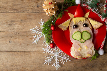 edible bull, symbol of 2021. A funny sandwich in the shape of a bull made of ham, cheese, bread, with a cucumber. children's breakfast.  New Year's, Christmas food.