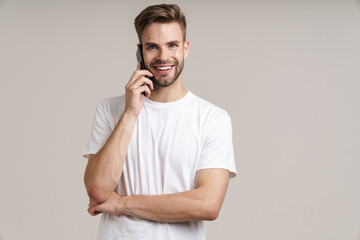 Photo of joyful handsome guy talking on mobile phone