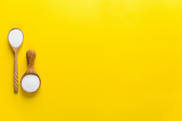 Collagen powder in wooden spoons on a yellow background. Dietary supplement. Horizontal orientation, top view, copy space.