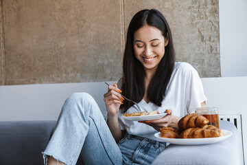 Woman sitting at home indoors and having a breakfast