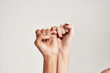 Close up of two female hands making a pinkie promise sign isolated over grey background. The symbol of commitment.