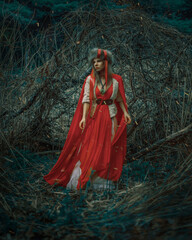 Portrait of a woman in a traditional costume, standing in an alcove of branches, in the forest