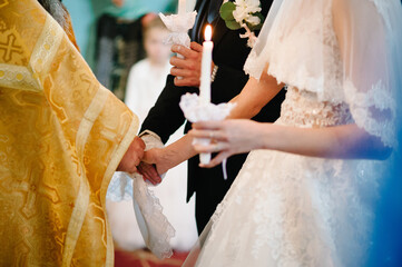 Hands of bride and groom tied Wedding towel. The priest binds the bride's hand towel. hands of young couples in the church. Wedding day.