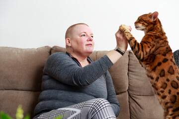 Woman playing with cat on sofa - 383838137