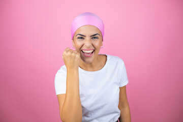 Young beautiful woman wearing pink headscarf over isolated pink background angry and mad raising...