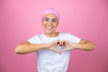 Young beautiful woman wearing pink headscarf over isolated pink background smiling in love showing...