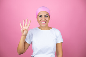 Young beautiful woman wearing pink headscarf over isolated pink background showing and pointing up with fingers number four while smiling confident and happy