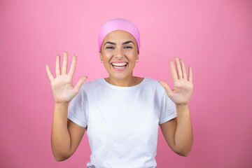 Fototapeta na wymiar Young beautiful woman wearing pink headscarf over isolated pink background showing and pointing up with fingers number ten while smiling confident and happy