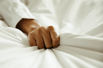 Close up hand of female pulling white sheets in ecstasy , feeling and emotion concept